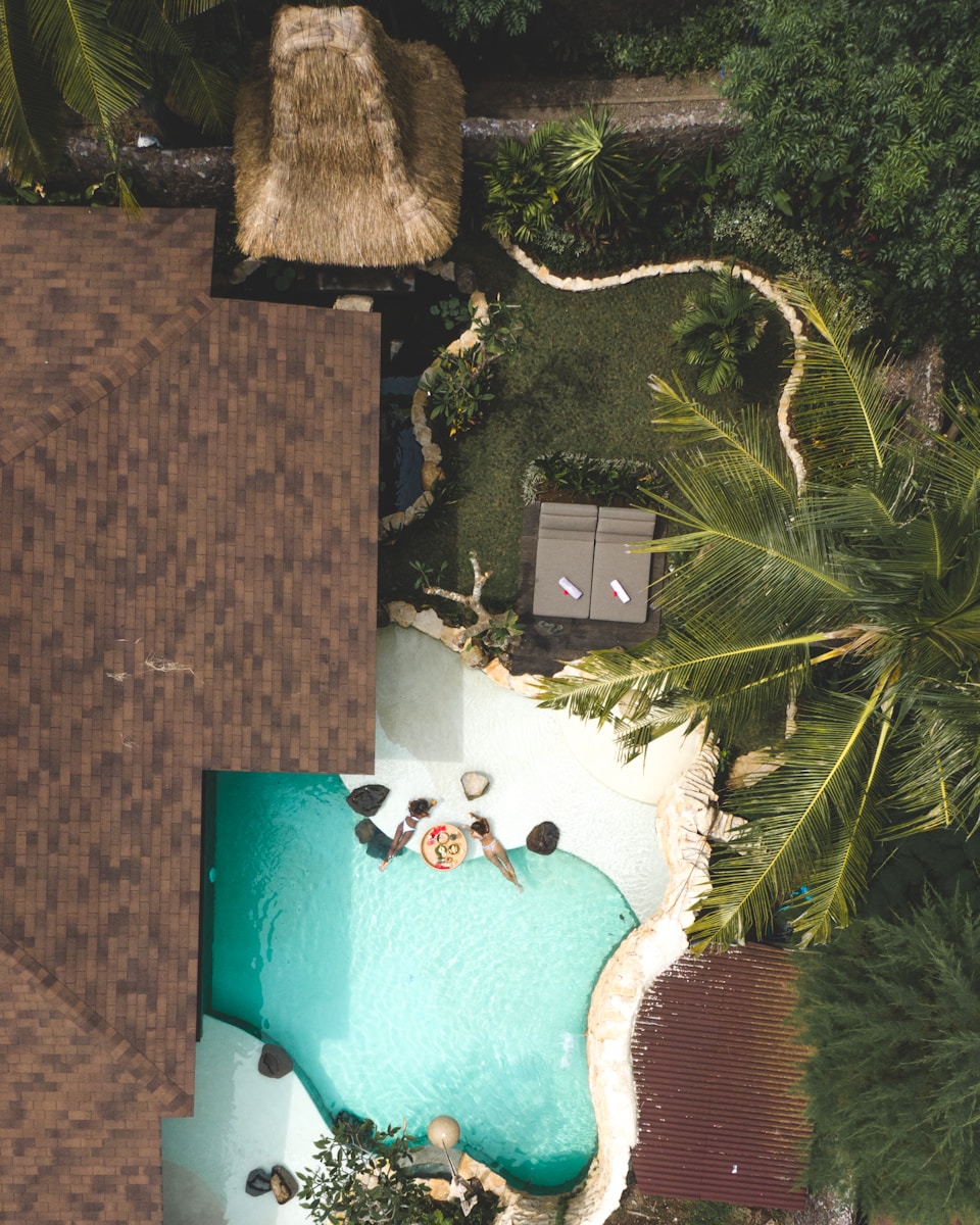 Photo by We Do Creative Films an aerial view of a pool surrounded by palm trees